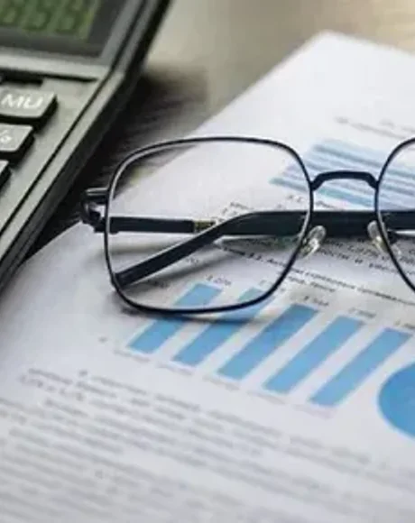 Relatório contábil com gráficos, calculadora e óculos sobre a mesa